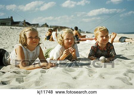 1950s 3 children lying on the beach at the jersey shore View Large Photo Image Stock Photo - 1950s 3 children lying on the beach at the jersey shore. Fotosearch