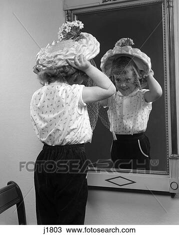 1950s child trying on hat looking at mirror reflection View Large Photo Image Stock Image - 1950s child trying on hat looking at mirror reflection. Fotosearch