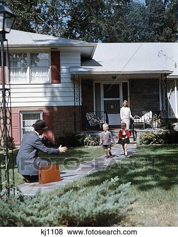 1950s father coming home kneeling arms extended boy girl running to welcome him woman stand suburban house family View Large Photo Image Stock Photo - 1950s father coming home kneeling arms extended boy girl running to welcome him woman stand suburban house family. Fotosearch