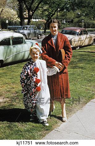 Stock Image - 1950s mother with son dressed in clown suit outdoors. Fotosearch