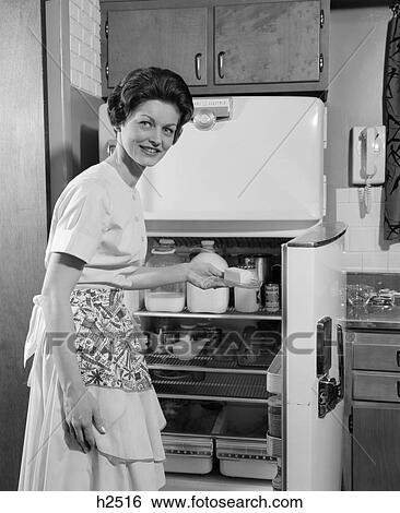1950s smiling woman housewife putting stick of butter into electric refrigerator in kitchen looking at camera View Large Photo Image Stock Photograph - 1950s smiling woman housewife putting stick of butter into electric refrigerator in kitchen looking at camera. Fotosearch