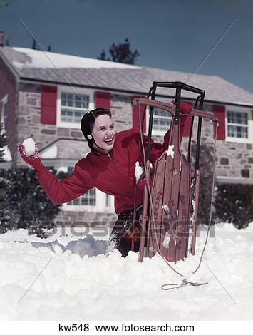 1950s woman hiding behind sled throwing snowball front stone house View Large Photo Image Stock Photo - 1950s woman hiding behind sled throwing snowball front stone house. Fotosearch