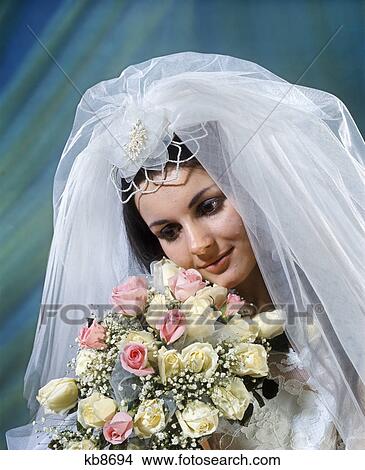1960s 1970s bride wearing veil holding bouquet pink yellow roses baby's breath View Large Photo Image Picture - 1960s 1970s bride wearing veil holding bouquet pink yellow roses baby's breath. Fotosearch