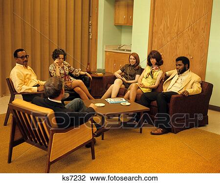 Stock Image - 1960s 1970s group men women sitting at coffee table meeting group therapy. Fotosearch
