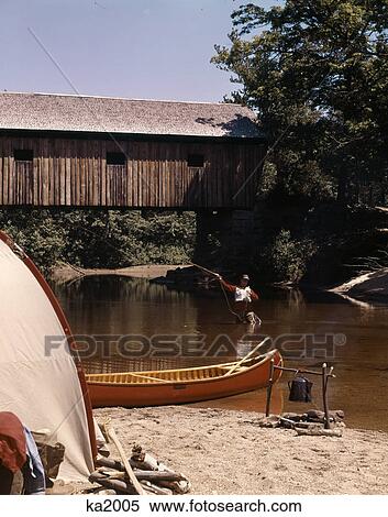 1960s 1970s man fly-fishing standing in stream by covered bridge and campsite with tent canoe campfire View Large Photo Image Stock Photography - 1960s 1970s man fly-fishing standing in stream by covered bridge and campsite with tent canoe campfire. Fotosearch