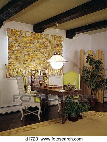 Stock Image - 1960s 1970s two matched wing chairs desk table print roman window shade houseplants checkerboard. Fotosearch