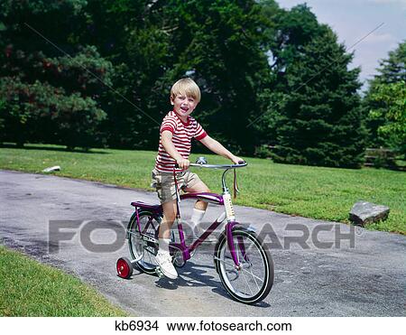 1960s 1970s young blond boy riding bike with training wheels View Large Photo Image Picture - 1960s 1970s young blond boy riding bike with training wheels. Fotosearch