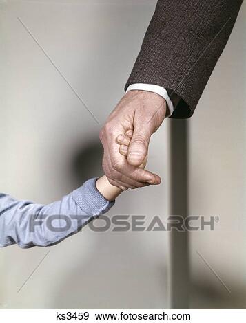 Stock Photo - 1960s adult man hand holding that of small child toddler father young old safety protection guidance. Fotosearch