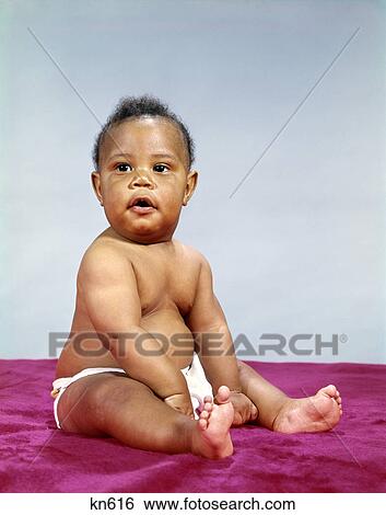 Stock Photograph - 1960s african-american baby boy wearing diaper portrait serious expression. Fotosearch