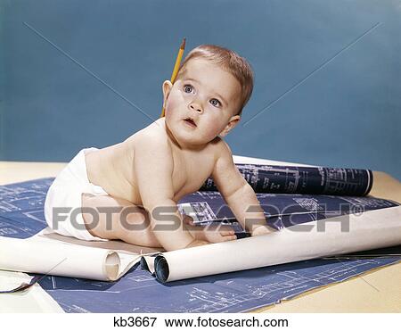 Stock Photo - 1960s baby architect sitting among blueprints. Fotosearch