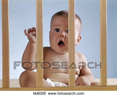 1960s baby in crib looking through bars arm raised open mouth View Large Photo Image Stock Photograph - 1960s baby in crib looking through bars arm raised open mouth. Fotosearch
