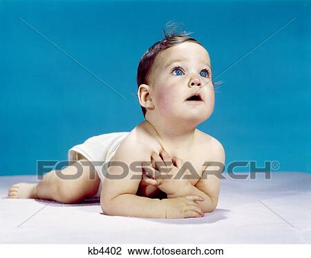 1960s baby lying on stomach looking up hand to chest with sincere facial expression awe wonder View Large Photo Image Stock Image - 1960s baby lying on stomach looking up hand to chest with sincere facial expression awe wonder. Fotosearch