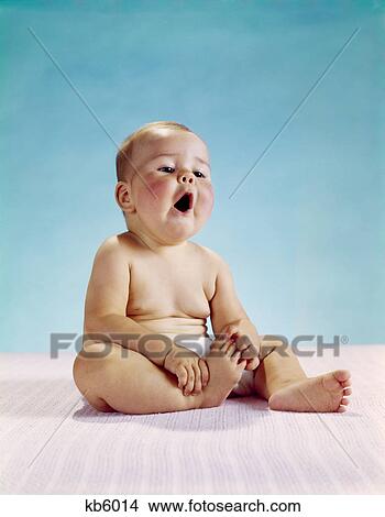 1960s baby sitting holding on to one foot mouth open awe wonder yawn understanding facial expression View Large Photo Image Picture - 1960s baby sitting holding on to one foot mouth open awe wonder yawn understanding facial expression. Fotosearch