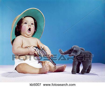 1960s baby wearing hat pith helmet holding gun big game hunter with stuffed elephant toy animal View Large Photo Image Stock Photo - 1960s baby wearing hat pith helmet holding gun big game hunter with stuffed elephant toy animal. Fotosearch