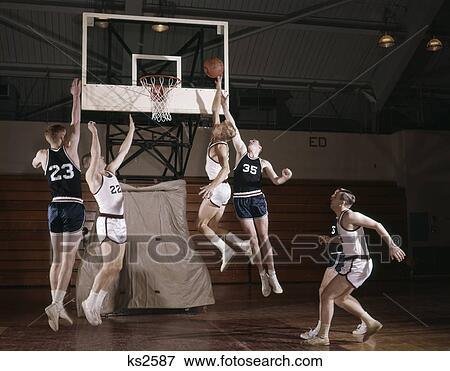1960s basketball players jumping for ball near hoop high school college team intramural one on one View Large Photo Image Stock Photo - 1960s basketball players jumping for ball near hoop high school college team intramural one on one. Fotosearch