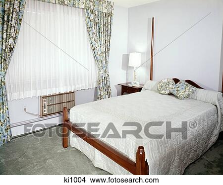 Picture - 1960s bedroom with full size bed window with floral print drapes sheers and air conditioner. Fotosearch