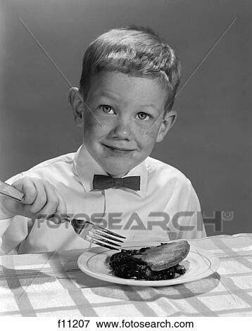 1960s boy wearing bow tie eating pie dessert with fork View Large Photo Image Stock Photo - 1960s boy wearing bow tie eating pie dessert with fork. Fotosearch