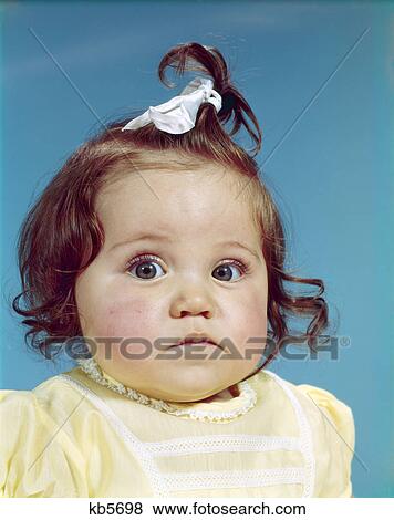 1960s brunette baby girl ribbon topknot yellow shirt chubby cheeks round face sad unhappy facial expression View Large Photo Image Stock Photo - 1960s brunette baby girl ribbon topknot yellow shirt chubby cheeks round face sad unhappy facial expression. Fotosearch