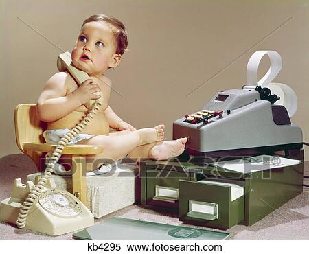 Stock Photography - 1960s business baby sitting booster chair holding telephone with calculator adding machine file drawers. Fotosearch
