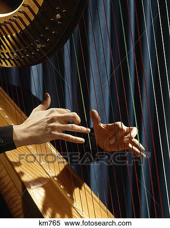 Stock Photography - 1960s close up of woman's hands playing harp plucking strings. Fotosearch