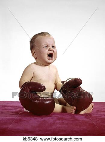 1960s crying baby wearing large boxing gloves sitting on red blanket View Large Photo Image Stock Photo - 1960s crying baby wearing large boxing gloves sitting on red blanket. Fotosearch