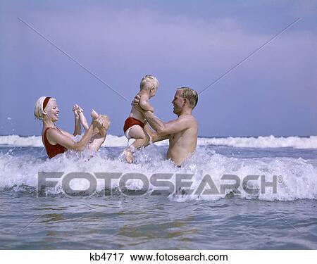 Stock Photo - 1960s family playing in ocean surf. Fotosearch