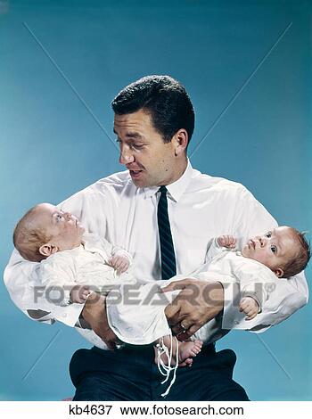 Stock Photo - 1960s father holding twin babies infants. Fotosearch
