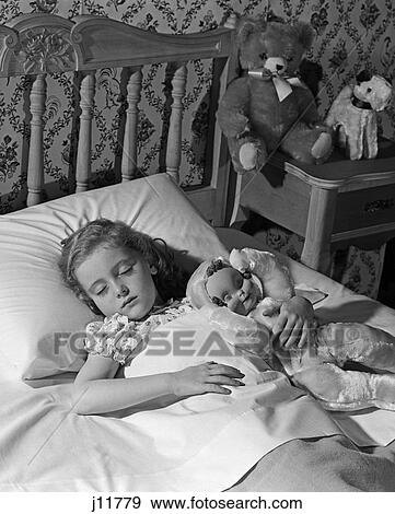 Stock Photo - 1960s girl child sleeping bed with doll. Fotosearch