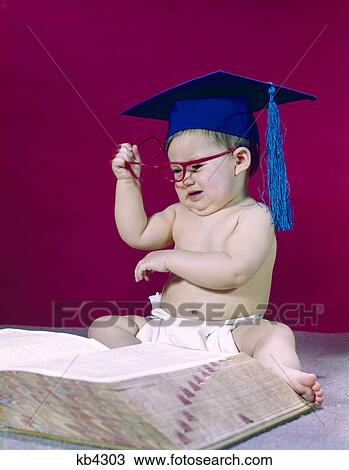 Stock Image - 1960s graduate professor baby wearing academic cap mortarboard eyeglasses reading book dictionary angry frustrated. Fotosearch