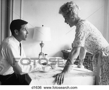 Stock Photograph - 1960s husband and wife arguing at breakfast table indoor. Fotosearch