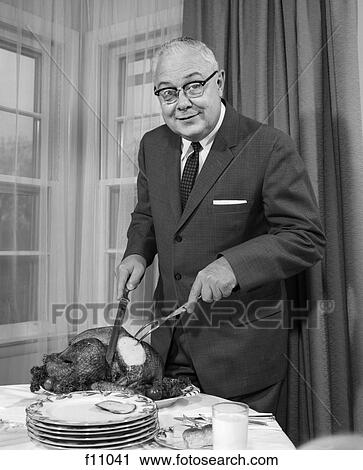 Stock Image - 1960s man carving turkey dinner thanksgiving. Fotosearch