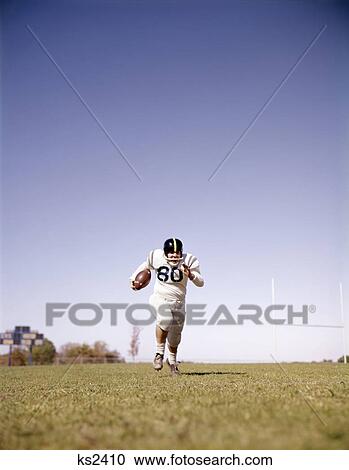 1960s man football player carrying ball running towards camera View Large Photo Image Stock Image - 1960s man football player carrying ball running towards camera. Fotosearch