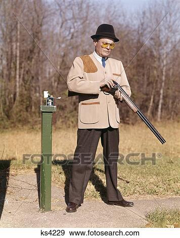 1960s man hunter loading shotgun while shooting skeet sport outdoors View Large Photo Image Stock Photo - 1960s man hunter loading shotgun while shooting skeet sport outdoors. Fotosearch