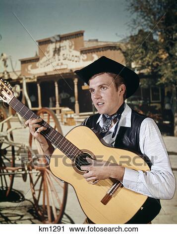 1960s man playing acoustic guitar cowboy saloon in background View Large Photo Image Stock Image - 1960s man playing acoustic guitar cowboy saloon in background. Fotosearch