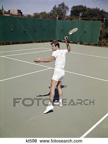 1960s man playing tennis swinging racket to hit ball action recreation exercise View Large Photo Image Stock Photo - 1960s man playing tennis swinging racket to hit ball action recreation exercise. Fotosearch
