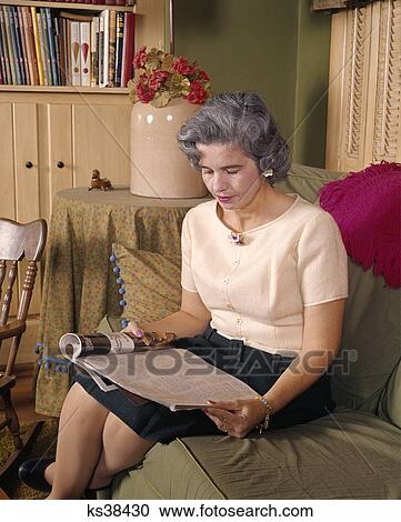 1960s middle aged woman sitting and reading magazine View Large Photo Image Stock Image - 1960s middle aged woman sitting and reading magazine. Fotosearch