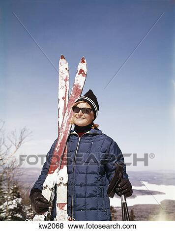1960s portrait smiling woman outdoors wearing quilted down jacket sunglasses holding skis View Large Photo Image Stock Photo - 1960s portrait smiling woman outdoors wearing quilted down jacket sunglasses holding skis. Fotosearch