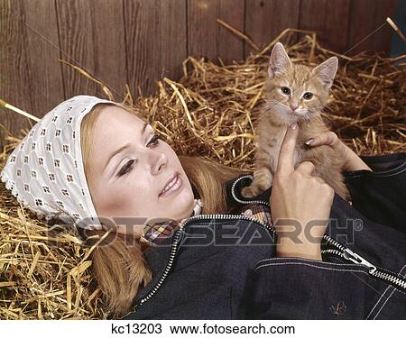 1960s portrait young blond woman lying barn straw hay holding red tabby kitten pet View Large Photo Image Stock Image - 1960s portrait young blond woman lying barn straw hay holding red tabby kitten pet. Fotosearch