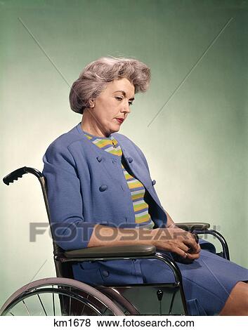 Stock Photo - 1960s sad senior woman sitting in wheelchair. Fotosearch