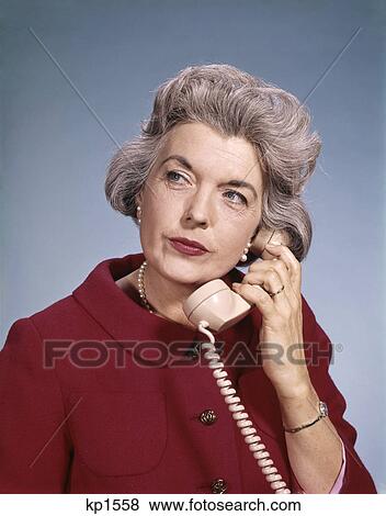 1960s senior middle aged woman red blouse serious expression talking on telephone View Large Photo Image Stock Photo - 1960s senior middle aged woman red blouse serious expression talking on telephone. Fotosearch
