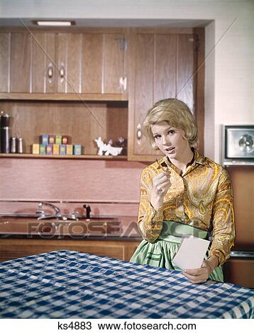 1960s serious blonde housewife making shopping list at kitchen table View Large Photo Image Stock Image - 1960s serious blonde housewife making shopping list at kitchen table. Fotosearch