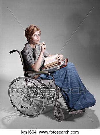 1960s serious young woman student sitting in wheelchair pile of books on lap View Large Photo Image Picture - 1960s serious young woman student sitting in wheelchair pile of books on lap. Fotosearch