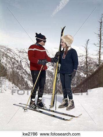 1960s smiling couple talking on ski slope wearing ski gear View Large Photo Image Stock Photograph - 1960s smiling couple talking on ski slope wearing ski gear. Fotosearch