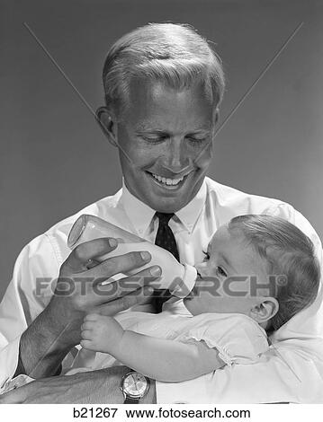 1960s smiling father feeding child milk in baby bottle View Large Photo Image Stock Photo - 1960s smiling father feeding child milk in baby bottle. Fotosearch