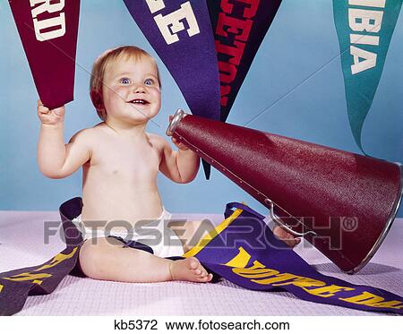 Stock Image - 1960s smiling happy baby with college pennants holding cheerleader megaphone. Fotosearch