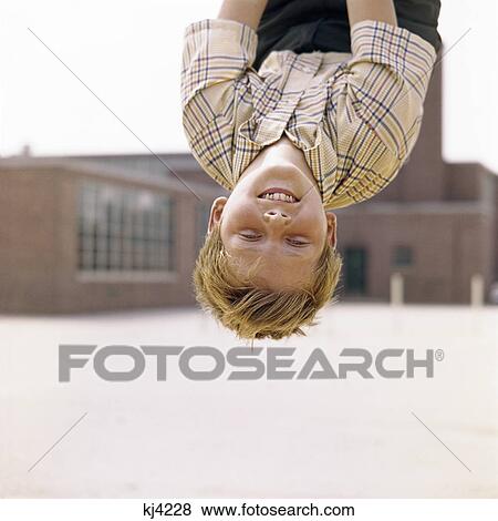 1960s smiling red haired boy hanging upside down in elementary school yard View Large Photo Image Stock Photo - 1960s smiling red haired boy hanging upside down in elementary school yard. Fotosearch