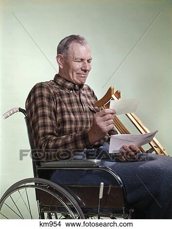 1960s smiling senior man sitting in wheelchair with crutches reading insurance check View Large Photo Image Picture - 1960s smiling senior man sitting in wheelchair with crutches reading insurance check. Fotosearch
