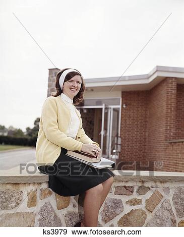 1960s smiling teen girl sweater & skirt sit on stone steps brick building high school student coed View Large Photo Image Stock Photo - 1960s smiling teen girl sweater & skirt sit on stone steps brick building high school student coed. Fotosearch