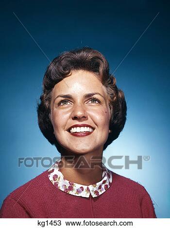 Stock Image - 1960s smiling woman looking up studio. Fotosearch
