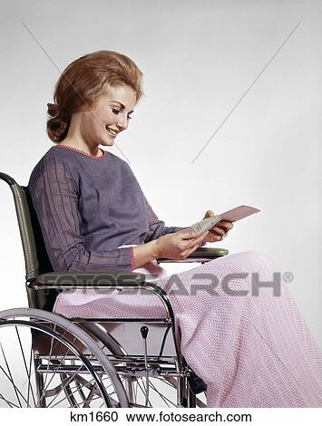 1960s smiling woman sitting in wheelchair reading insurance check View Large Photo Image Stock Image - 1960s smiling woman sitting in wheelchair reading insurance check. Fotosearch